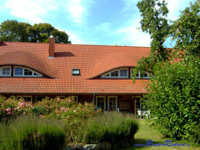 Blick durch den Gutsgarten auf die Terrassen der Ferienwohnungen