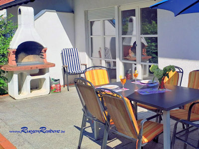 Die Terrasse mit Gartentisch und festem Grillkamin